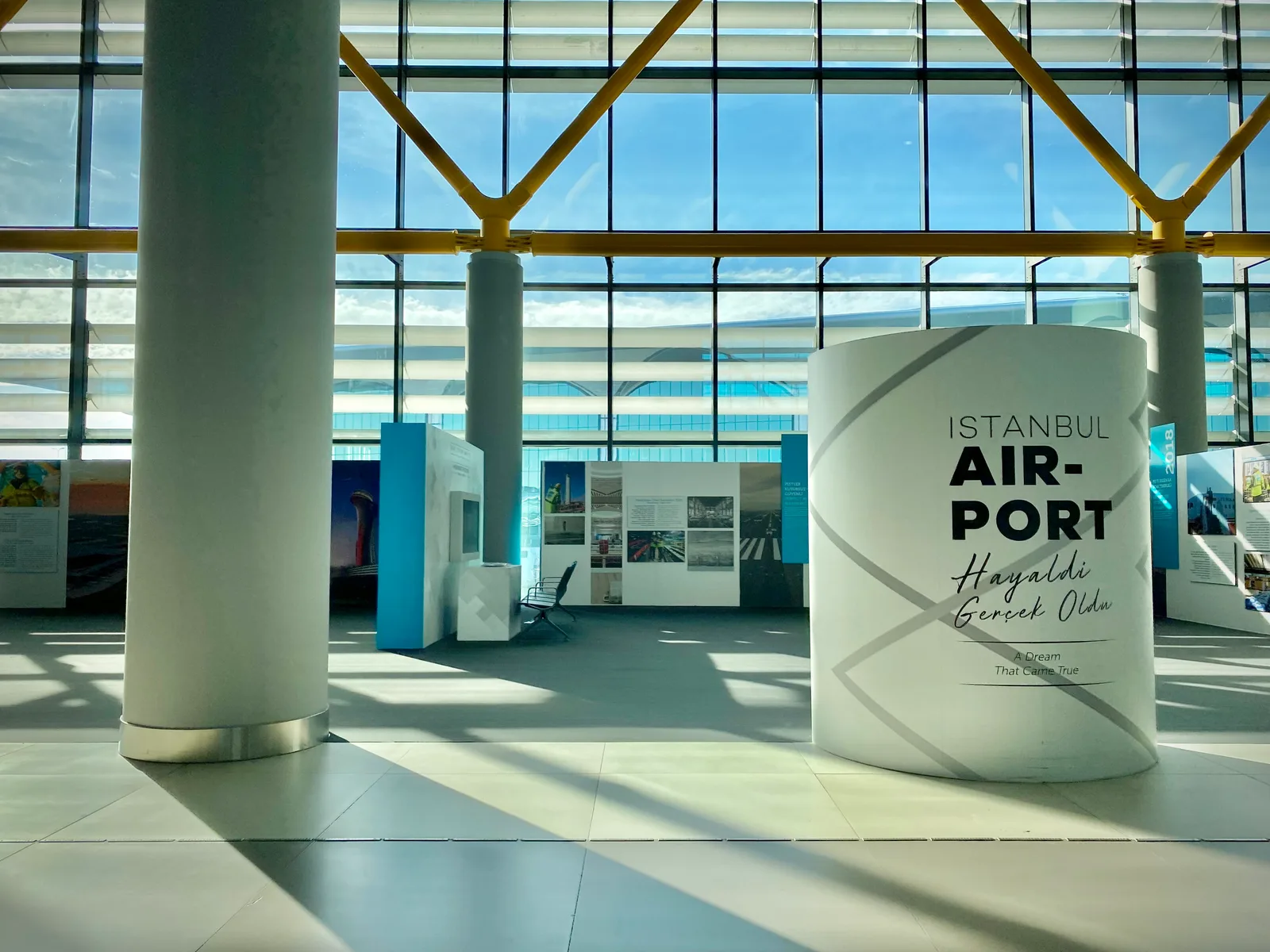 Intérieur du terminal de l’aéroport d’Istanbul avec de grandes baies vitrées et un panneau portant le nom de l’aéroport