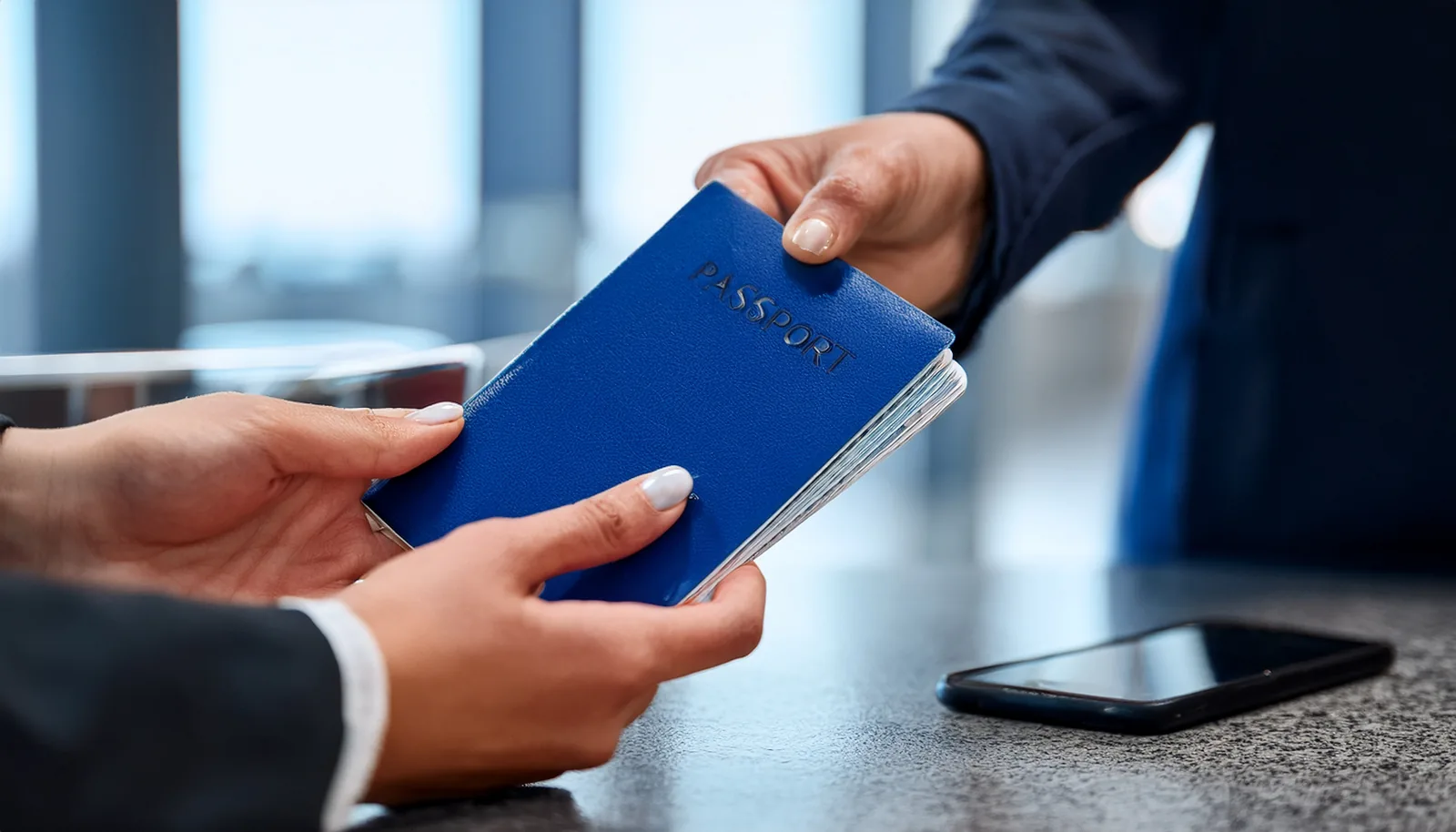 Mains tendant un passeport à un comptoir de porte d’embarquement, avec un téléphone portable posé sur le comptoir