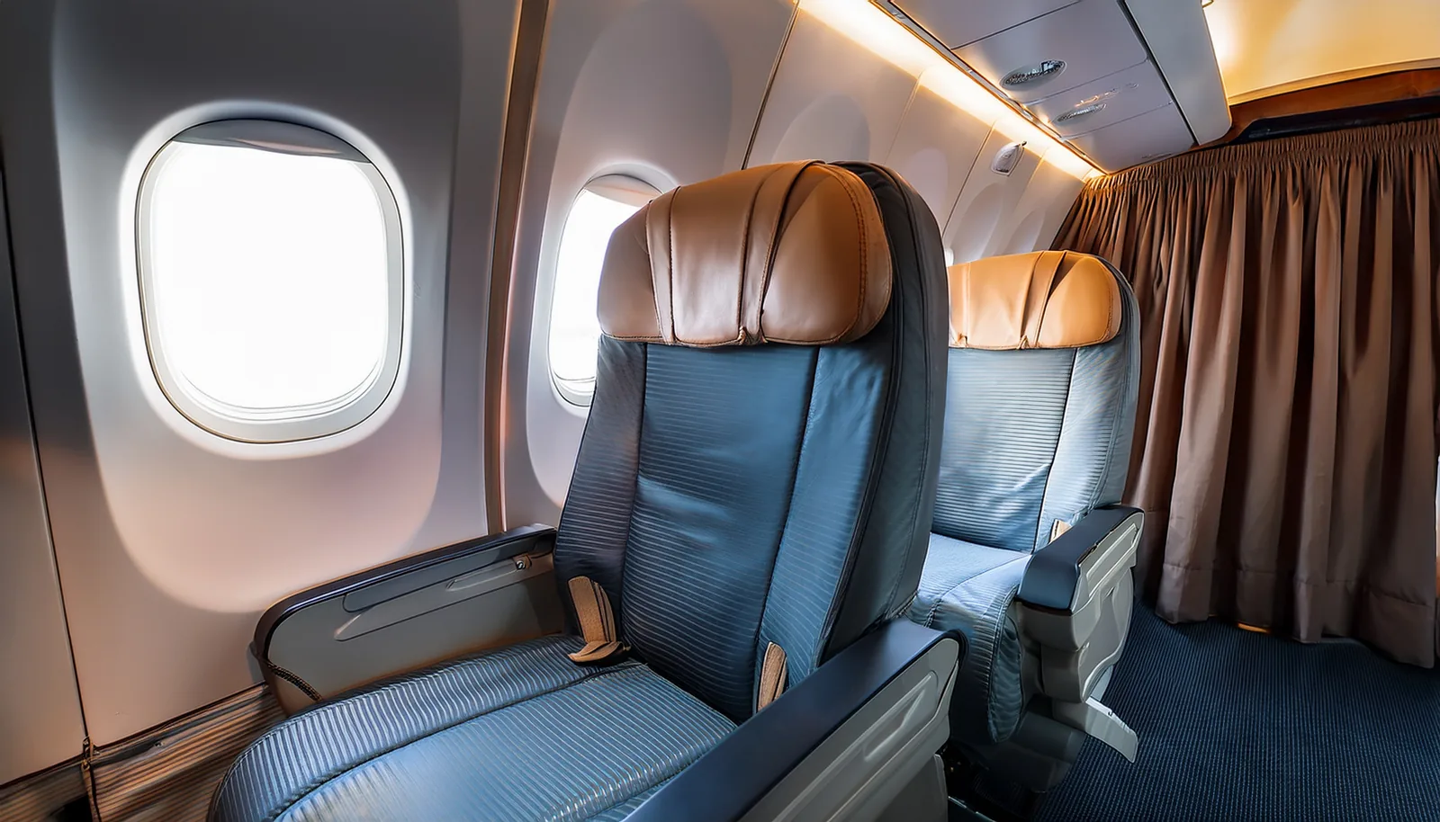 Un siège d’avion vide près du hublot, devant le rideau qui donne sur la classe de cabine suivante